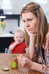 Obraz na płótnie Canvas Stressed Mother Trying To Feed Fussy Baby