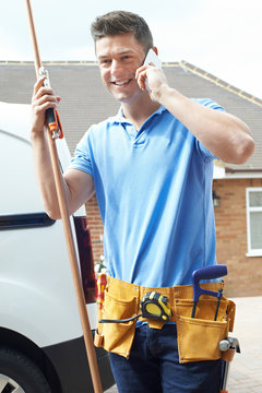Plumber With Van Talking On Mobile Phone Outside House