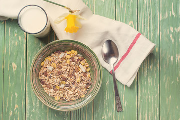 Bowl of oat flakes and glass of milk, on wooden background. Top view. Toned.