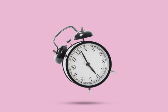 black alarm clock isolated on pink background.