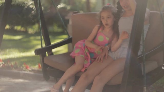 Two sisters are swinging on a swing in nature.