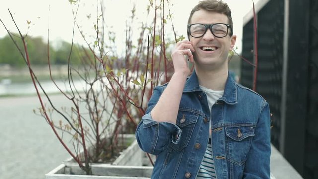 Stylish man receives good news while talking on cellphone, steadycam shot
