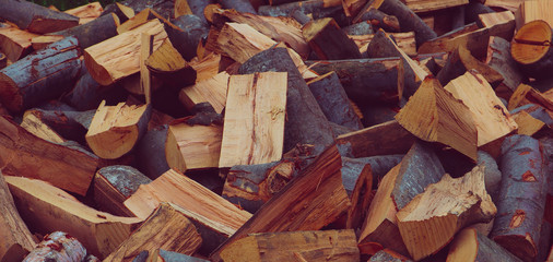 Chopped firewood on a stack, prepared for winter. Photo depicts a backdrop with birch firewood in a pile, hipster filter mood. Natural wooden background.