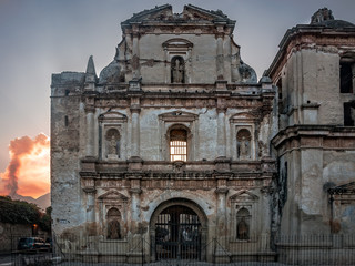 Facade of a ruined Church in Antigua, Guatemala with El Fuego volcano in the background.