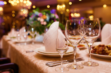 Sparkling glassware stands on long table prepared for wedding dinner

