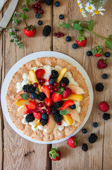Homemade dacquoise cake with wipped cream cheese garnished with summer berries and peaches, close up. Top view.