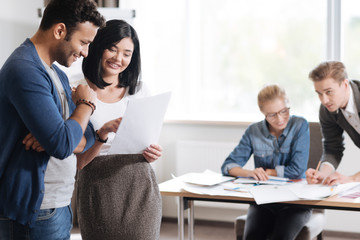 Delighted pleasant woman showing her colleague a document