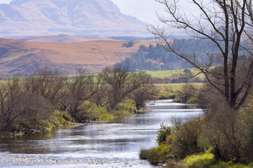 A river runs through the foothills of the Drakensberg Mountain Range at Underberg in South Africa.