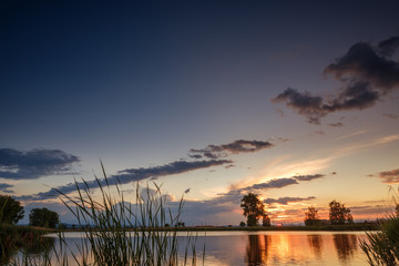Sunset over calm lake , sky reflection in water