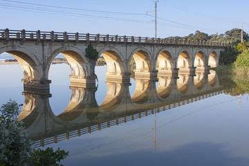 Reflection of a railway bridge crossing a calm lagoon on the KZN South Coast of South Africa.
