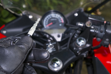 Biker in the black leather glove inserting key to starting the motorcycle engine