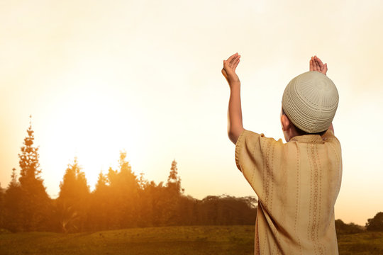 Back view of asian muslim kid with cap praying to god
