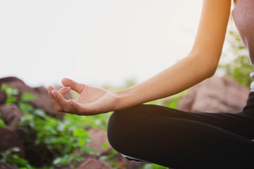 Beautiful women doing yoga in nature on a rock