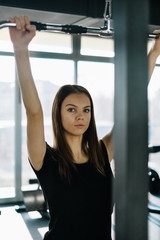 Young beautiful girl exercising in the fitness gym, with lat machine