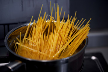 Spaghetti from durum wheat are cooked in a metal pot on the fire. Close