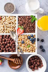 Variety of cold quick breakfast cereals with berries in white wooden box and other ingredients for breakfast, healthy eating concept, top view.