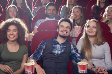 Front view of three smiling friends, two girls and one brunet man, spending free time...
