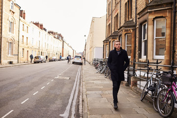 Young Man Walking Along Residential Street In Oxford