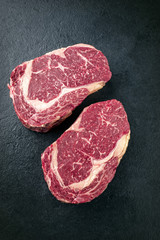 Two raw dry aged Kobe Entrecote Steak as close-up on a slate