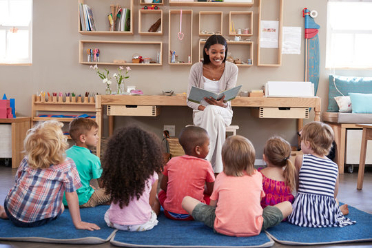 Teacher At Montessori School Reading To Children At Story Time