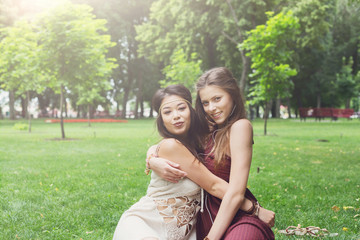 Two happy young girls hug each other in summer park
