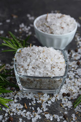 Sea salt scented herb rosemary on black stone background, natural light. Selective focus. 
