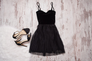 Little black dress and black shoes. Wooden background, fashionable concept
