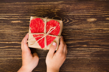 Children's hands hold gift box on a wooden table-top.A concept by the Mother's Day. Vintage toning....