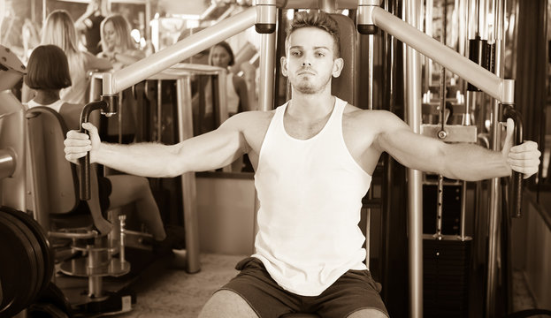 Young man using fly machine in gym.