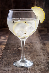 Glass of gin tonic with lemon on wooden background
