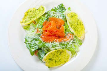 fresh caesar salad with salmon on white plate