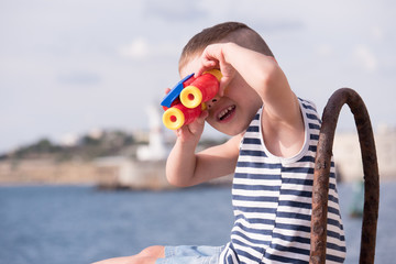 cheerful little boy looking into the distance through binoculars