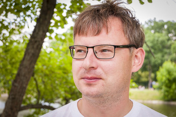 Young handsome and intelligent Caucasian man wearing glasses in the park.