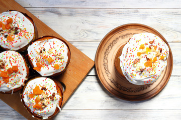 Many eastercake with multi-colored powder and candied fruit for cake with ceramic plate with cake on white wooden boards. Top view.