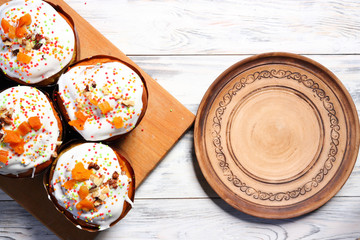 Many eastercake with multi-colored powder and candied fruit for cake with ceramic pottery handmade plate with cake on white wooden boards. Top view. Copy space
