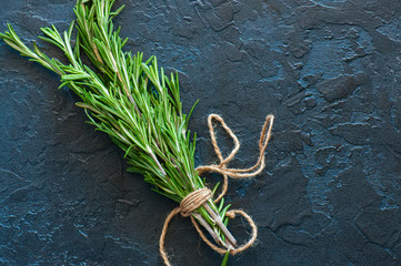Close up of bunch of fresh rosemary on a black slate background