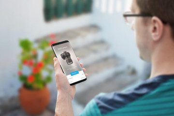 Online shopping with mobile phone. Man looking for camera online.