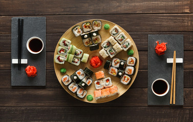 Fototapeta na wymiar Set of sushi maki and rolls on black rustic wood, top view