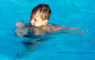 The boy is swimming in the pool