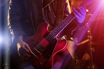 A rocker is playing guitar on stage. - obrazy, fototapety, plakaty