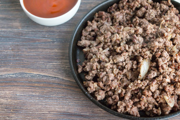 Fried minced meat with red sauce on wooden table. Ingredients for cooking. Top view. Copy space.