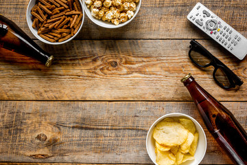 Fototapeta premium film whatching party with beer, crumbs, chips and pop corn wooden background top view mockup