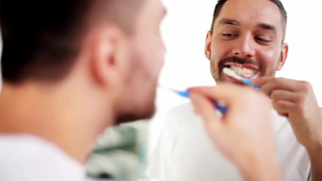 man with toothbrush cleaning teeth at bathroom