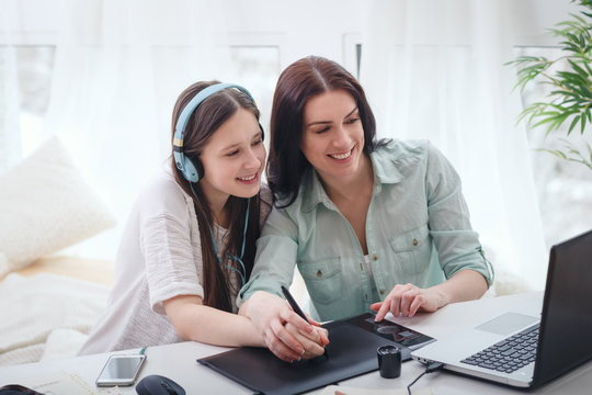 Beautiful woman and pretty teenager girl drawing illustrations together with digital tablet and stylus - Powered by Adobe