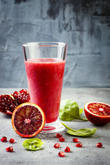 Detox fresh juice or smoothie in glass with blood oranges, greens, pomegranate. Homemade refreshing...