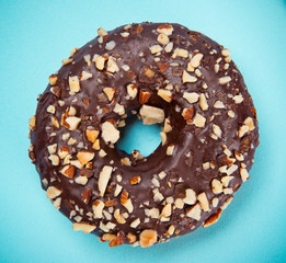 Glazed donut with colorful sprinkles on blue pastel background.