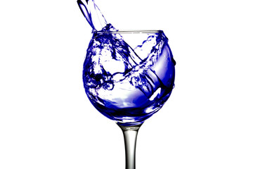 Purple water pours into a glass on a white background