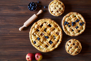 Homemade pastry apple pie pies bakery products on dark wooden kitchen table with raisins, blueberry...