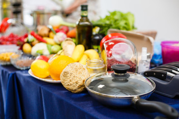 Casserole or frying pan with a glass lid on the table with a lot of vegetables abd other food