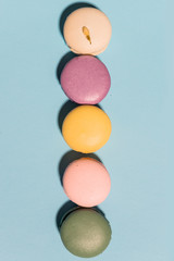 Five sweet colorful macaroons on blue table background.